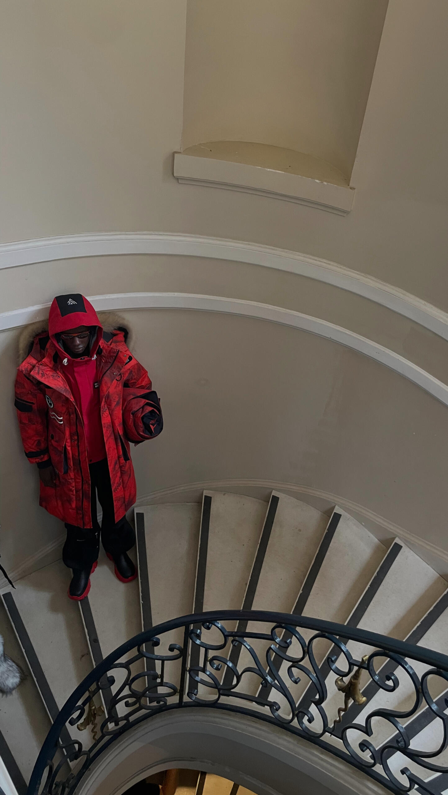 Modello con parka rosso su una scala a chiocciola