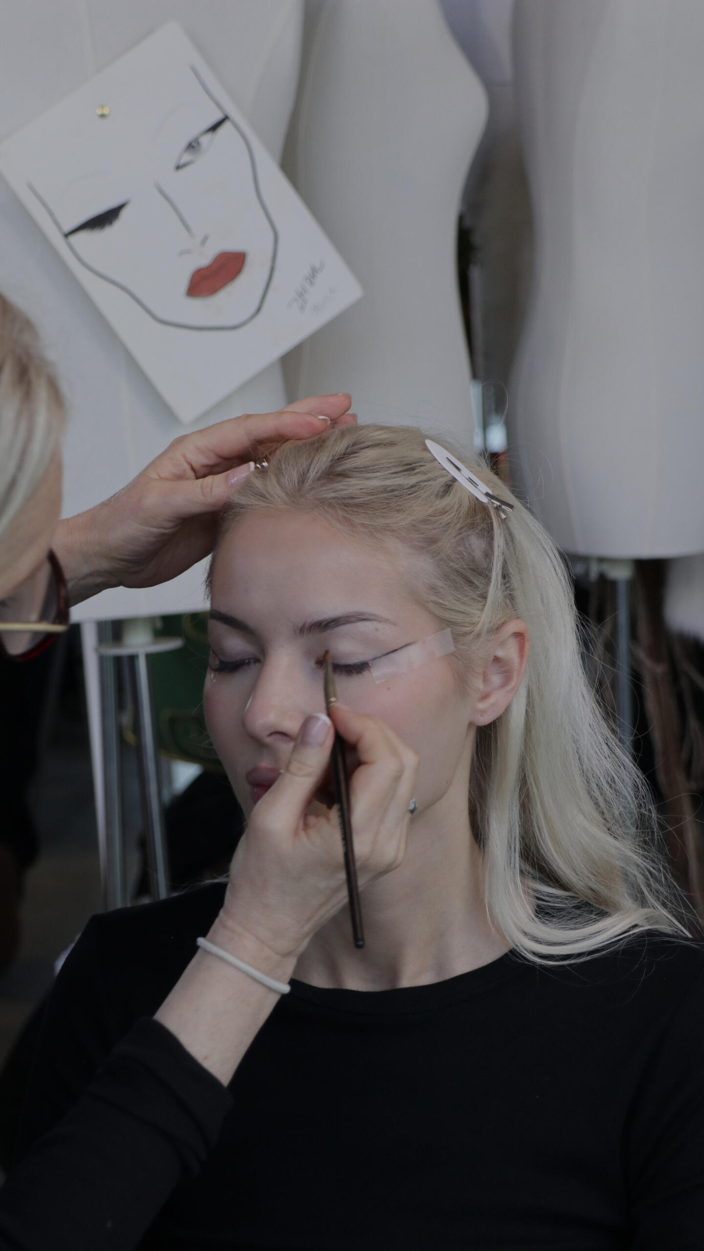Make-up artist traccia l'eyeliner a una modella bionda